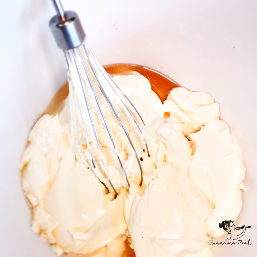 Whisking frosting ingredients in a bowl for low-carb honey cake