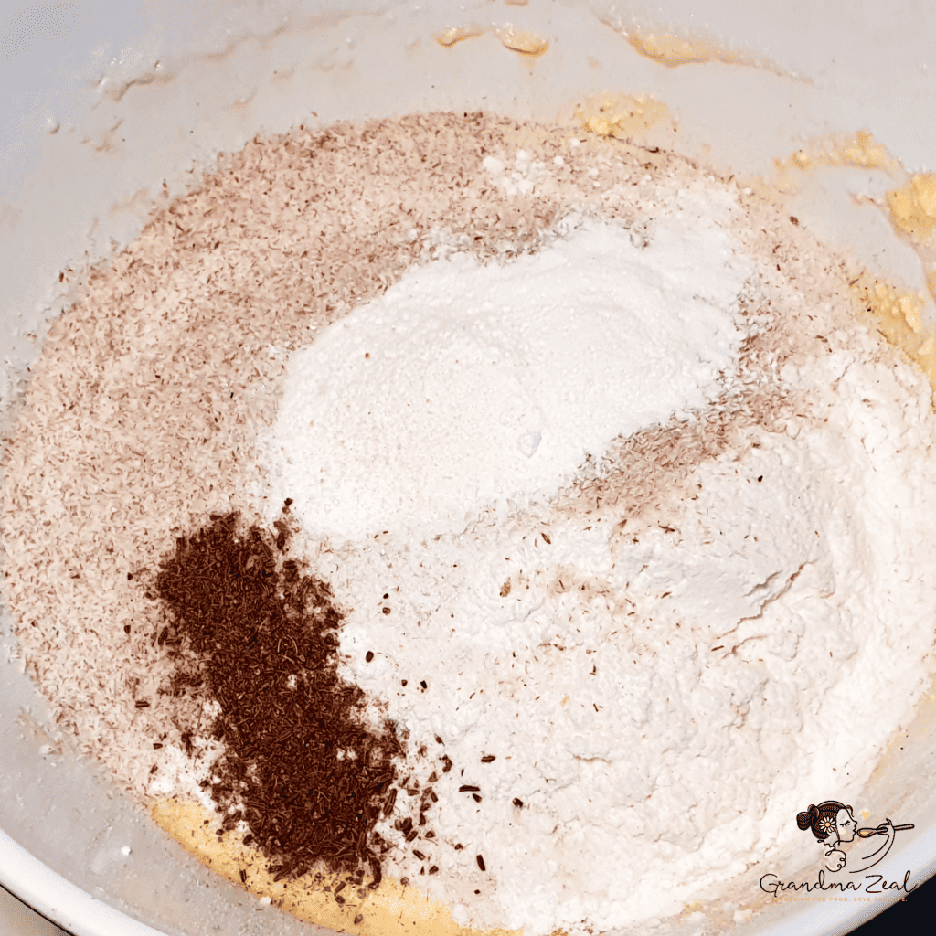 Dry ingredients including fibre, psyllium, and spices added to the egg and cheese mixture in a bowl for keto rye bread.