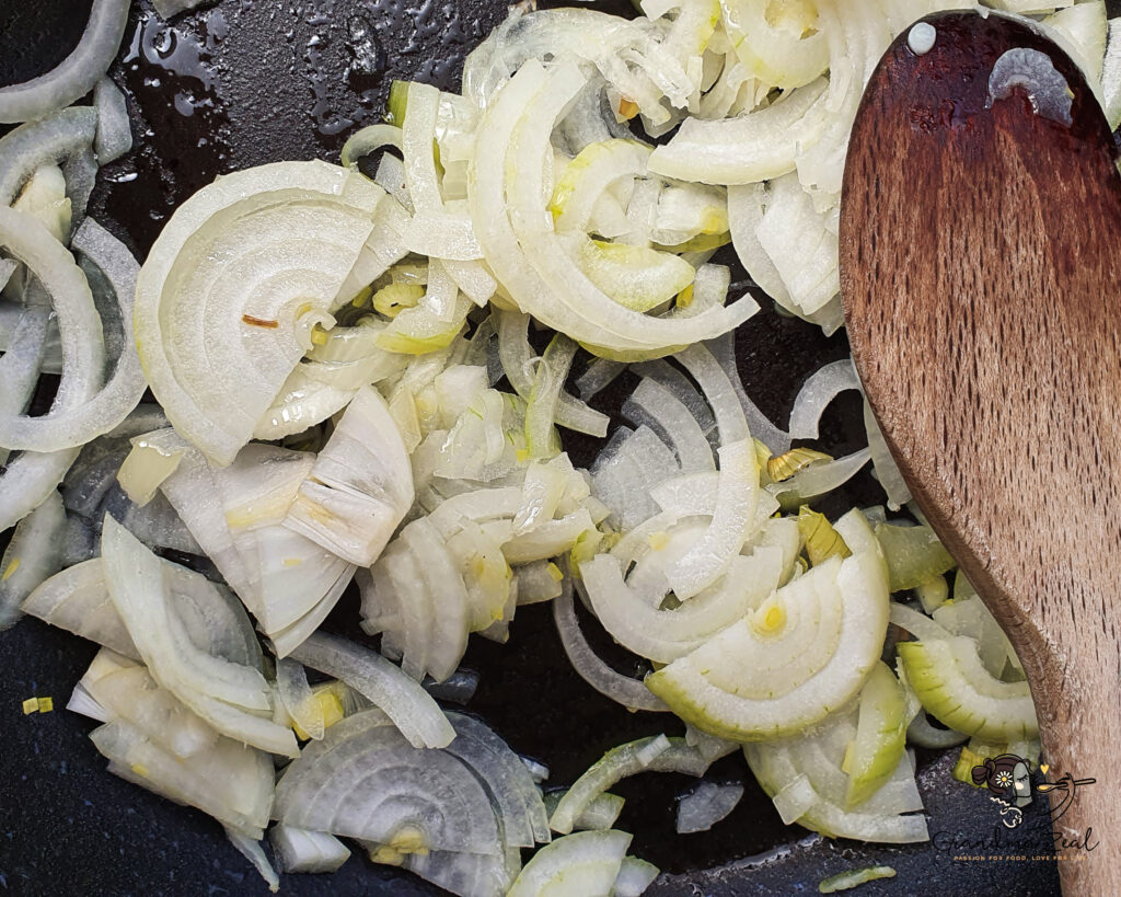 Sliced onion frying in a pan with oil