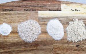 Four different types of dietary fibre ingredients displayed on a wooden chopping board
