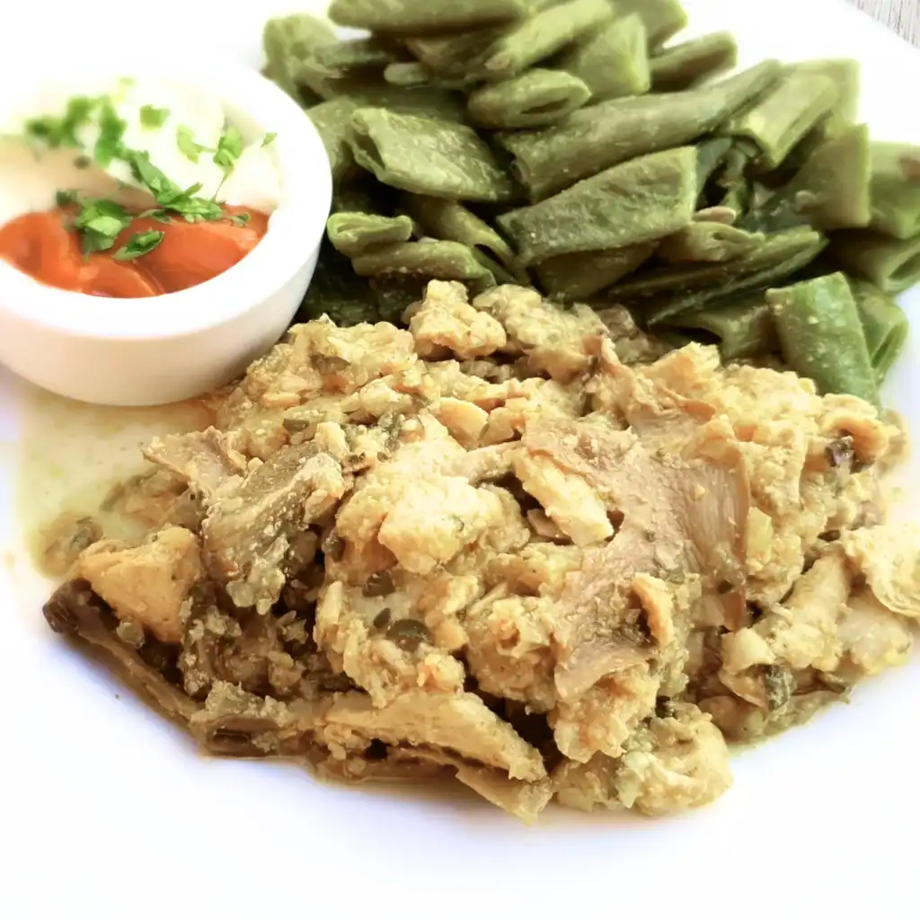 Chicken stroganoff with beans served on a plate, with small bowls of ketchup and mayonnaise on the side for extra flavour.