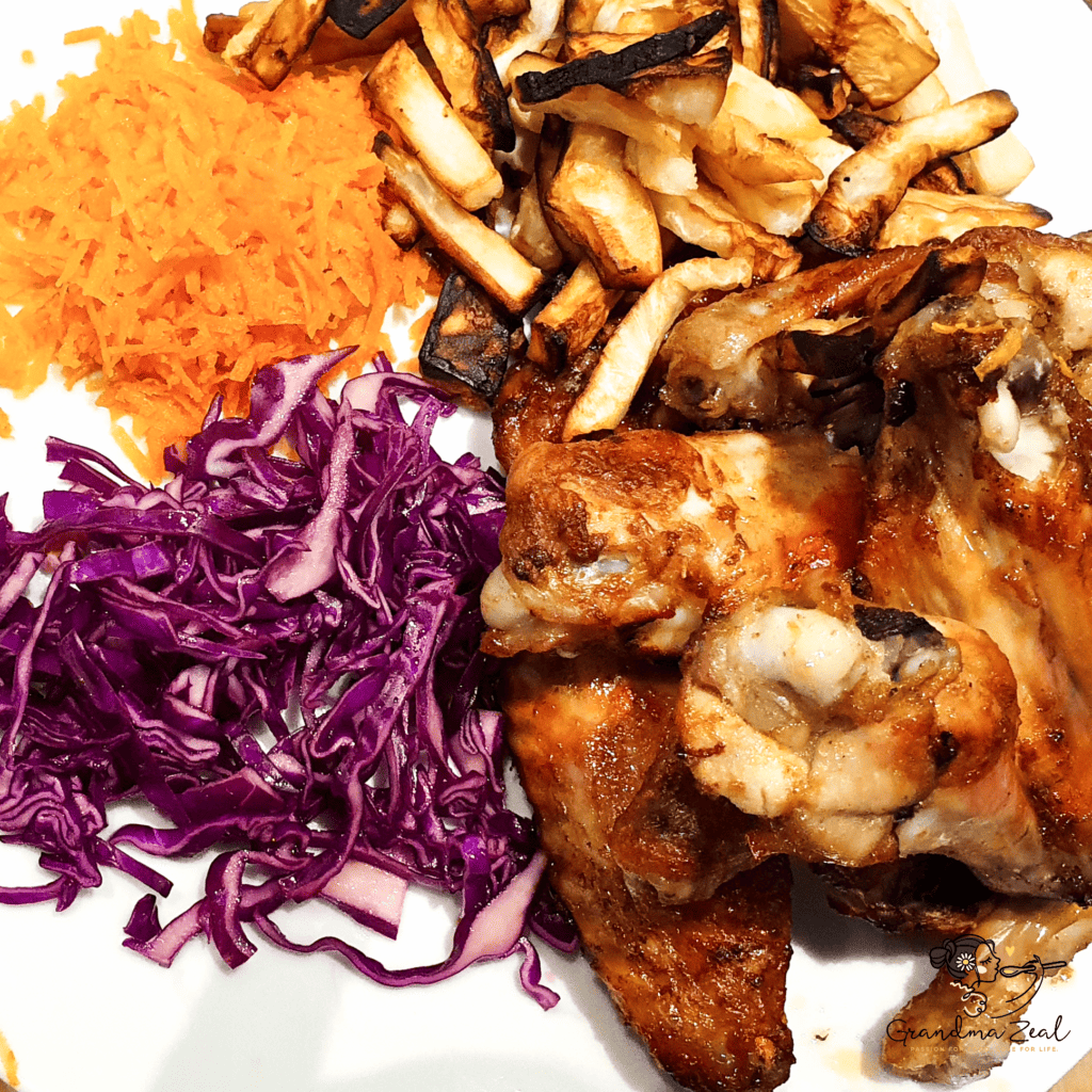 UNFORGETTABLE CHICKEN WINGS – CRISPY, JUICY & ADDICTIVE A plated portion of roast chicken served with roasted celeriac chips, grated carrots, and sliced red cabbage.