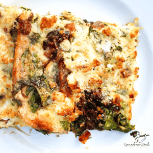 A portion of spinach and bacon crustless quiche served on a plate, showing its golden top and creamy, flavourful filling.