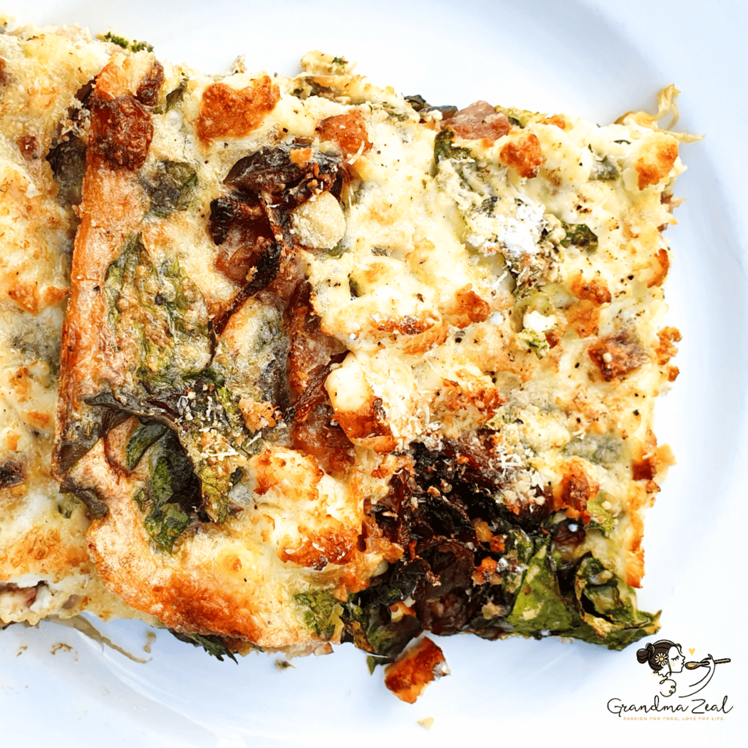 A portion of spinach and bacon crustless quiche served on a plate, showing its golden top and creamy, flavourful filling.