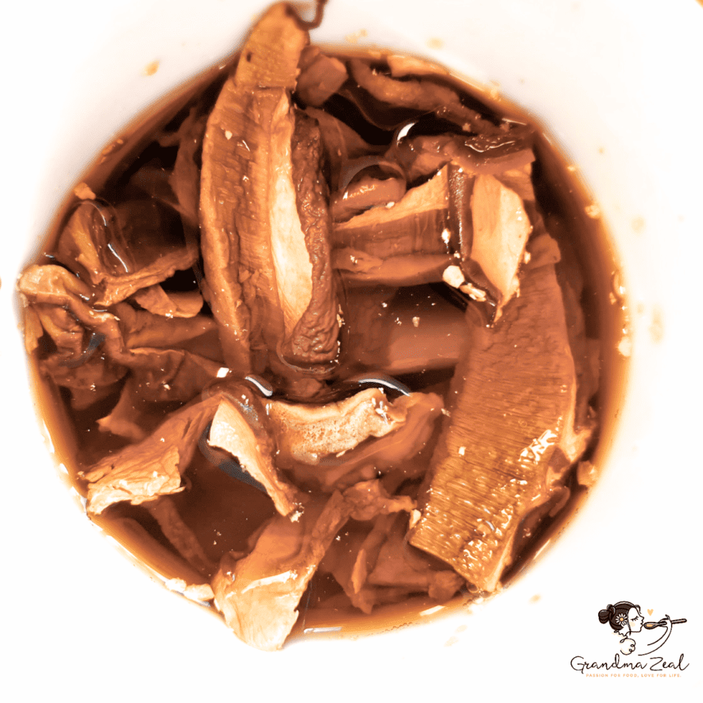 Dry wild mushrooms soaking in a cup of hot water, rehydrating before cooking.