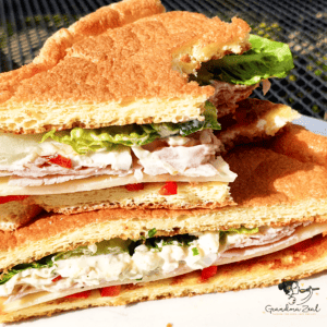 Close-up of a keto cloud bread sandwich with a bite taken out of the top triangle, filled with egg mayo, lettuce and ham.