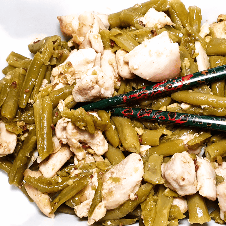 Close-up of garlic chicken with green beans, with chopsticks