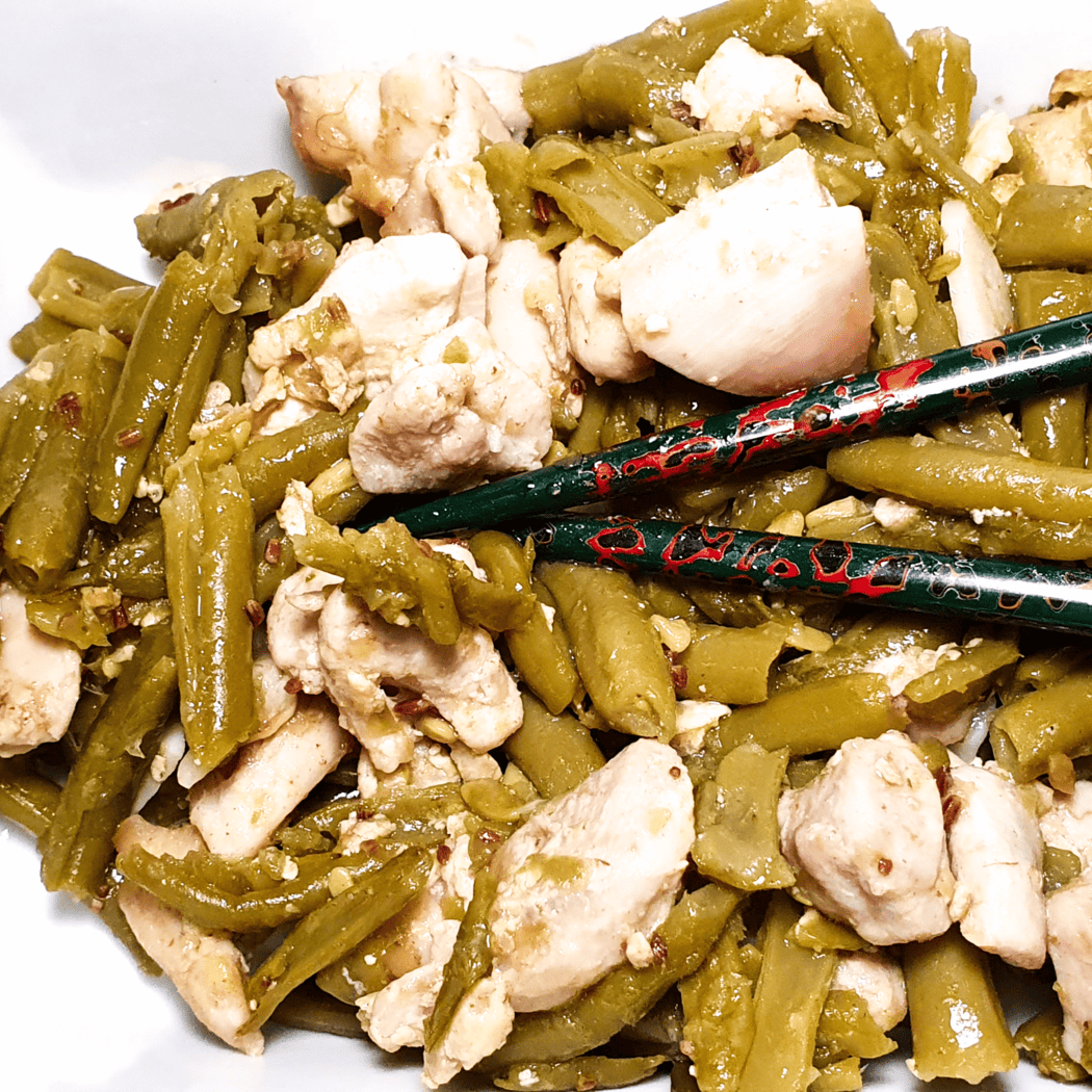 Close-up of garlic chicken with green beans, with chopsticks