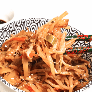 Easy chicken chow mein with vegetables, lifted by chopsticks from a bowl