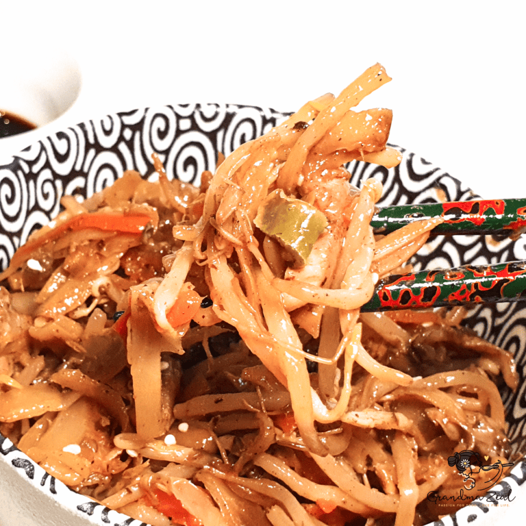 EASY CHICKEN CHOW MEIN RECIPE YOU CAN MAKE AT HOME Easy chicken chow mein with vegetables, lifted by chopsticks from a bowl