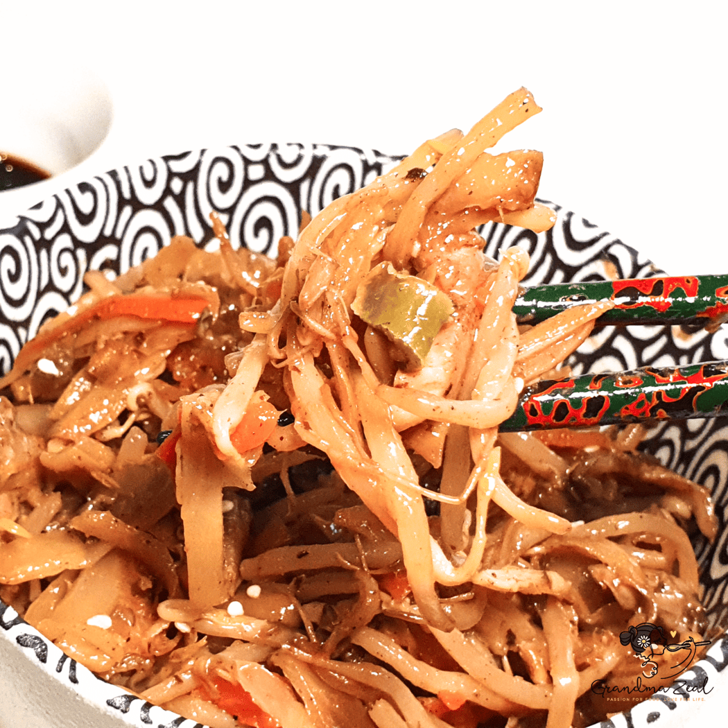 Easy chicken chow mein with vegetables, lifted by chopsticks from a bowl