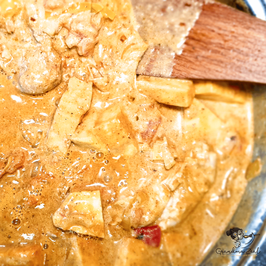 Close-up of stirring chicken-aubergine curry in the pan during cooking