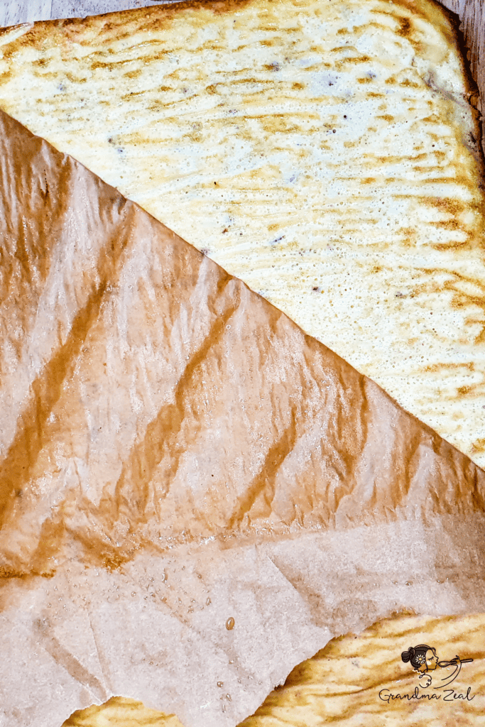 Illustration showing how to peel off parchment paper from freshly baked keto cloud bread.