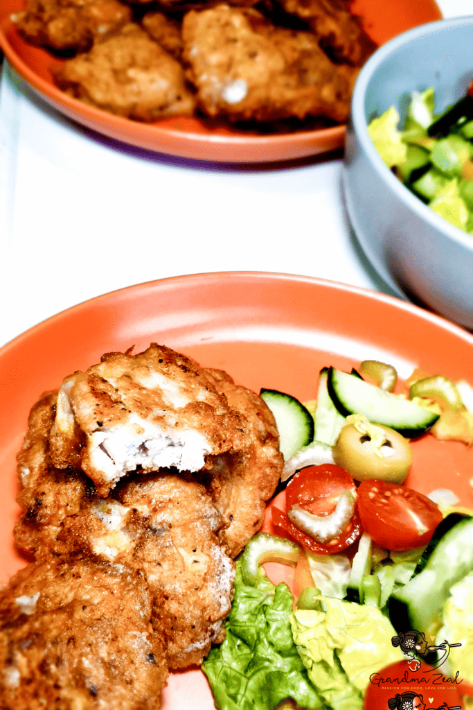 Serving fried chicken thighs with vegetable salad, with a plate full of fried chicken in the blurred background