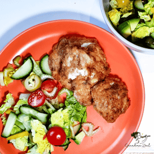 A few pieces of keto fried chicken served with Greek salad on a plate