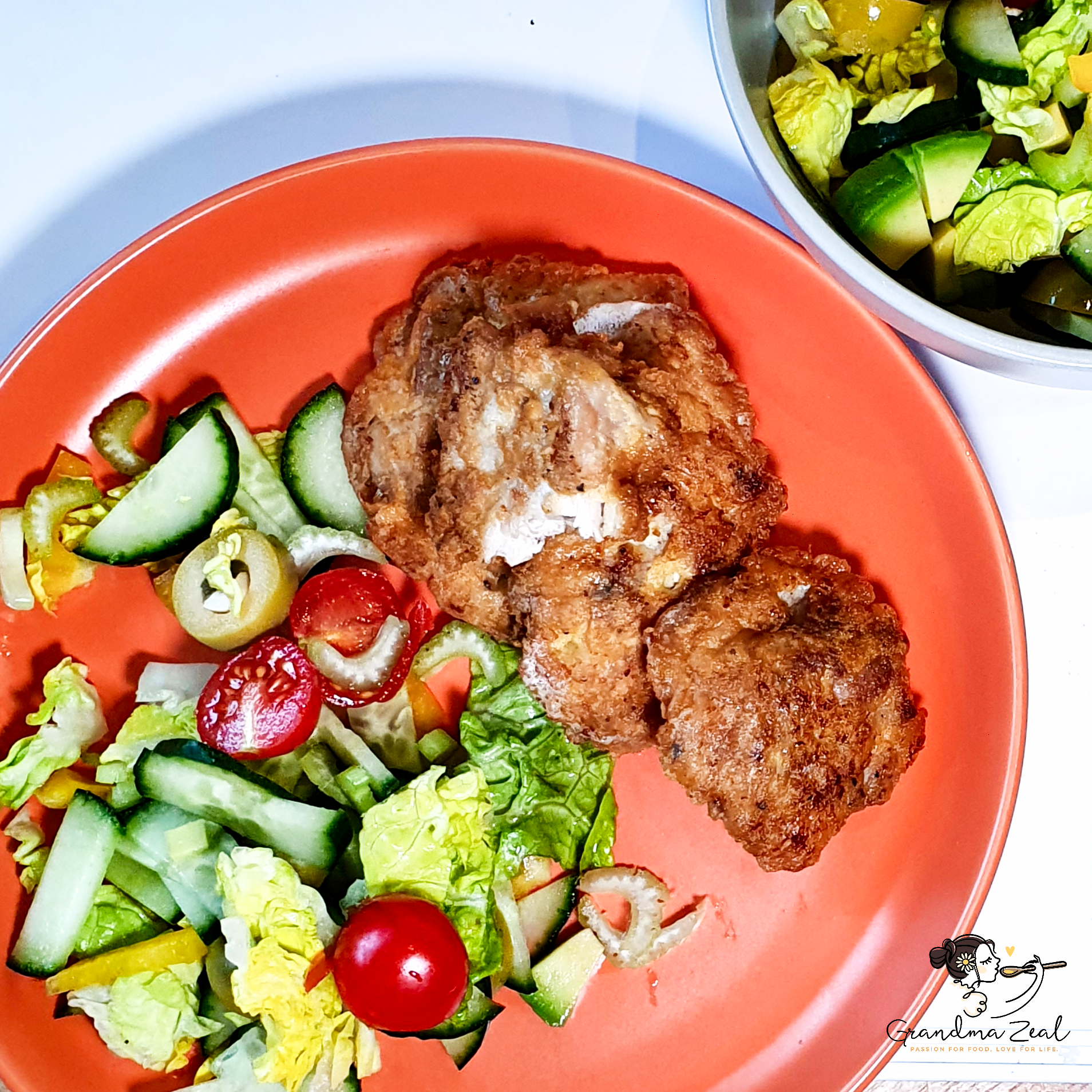 A few pieces of keto fried chicken served with Greek salad on a plate