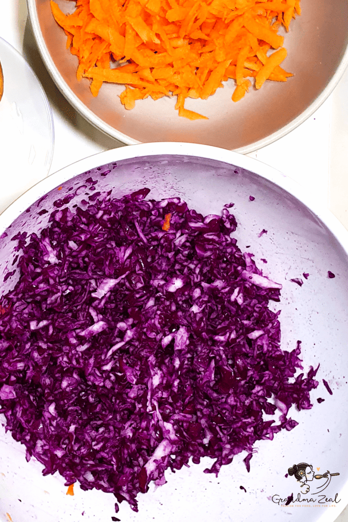 Two bowls side by side — one with shredded red cabbage, the other with grated carrots