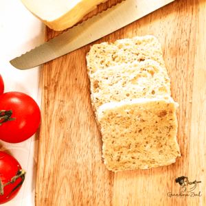 Sliced 90-second microwave bread on a wooden board with fresh tomatoes as decoration - feature pic