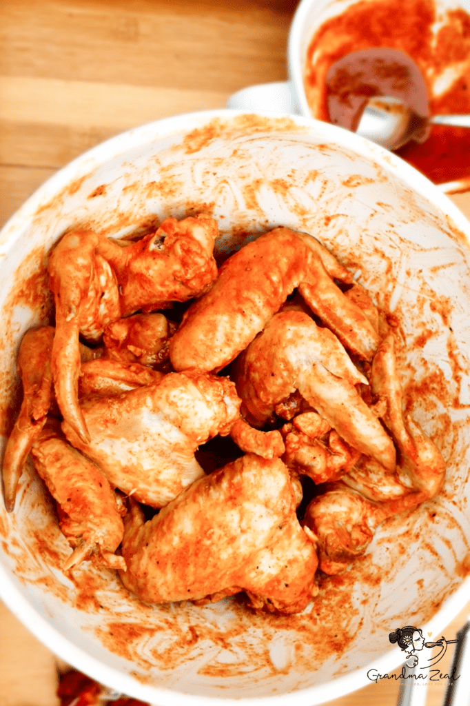 UNFORGETTABLE CHICKEN WINGS – CRISPY, JUICY & ADDICTIVE Raw chicken wings coated in a rich marinade with herbs and spices, resting in a mixing bowl before cooking.