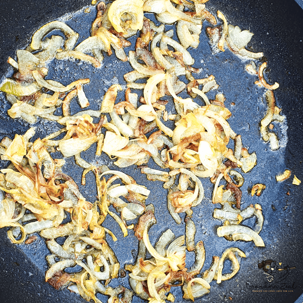 Lightly browned sliced onion frying in a pan, prepared for crustless quiche.