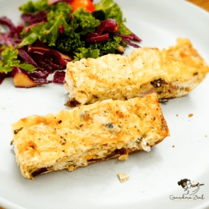 Two slices of spinach and bacon crustless quiche served with a fresh kale salad on the side.