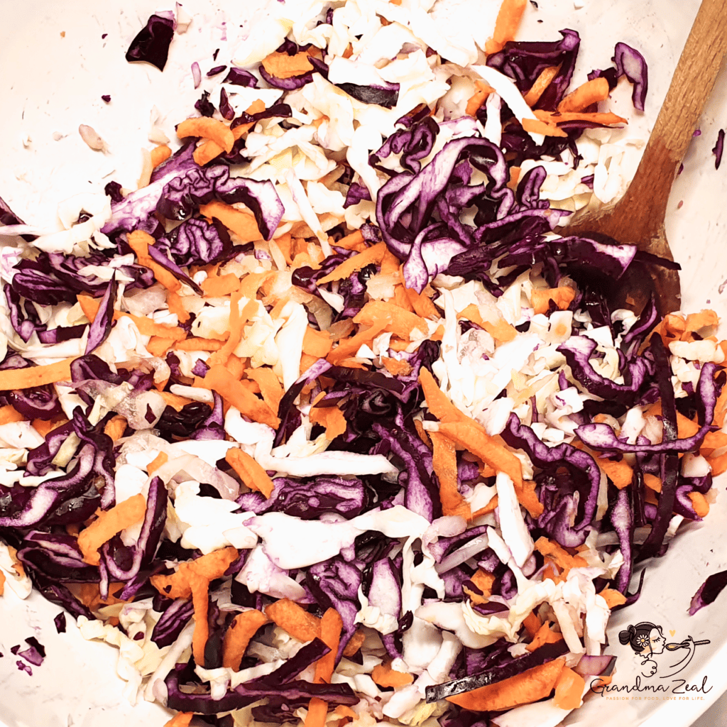 Shredded red and white cabbage, carrots, and onion mixed in a large bowl