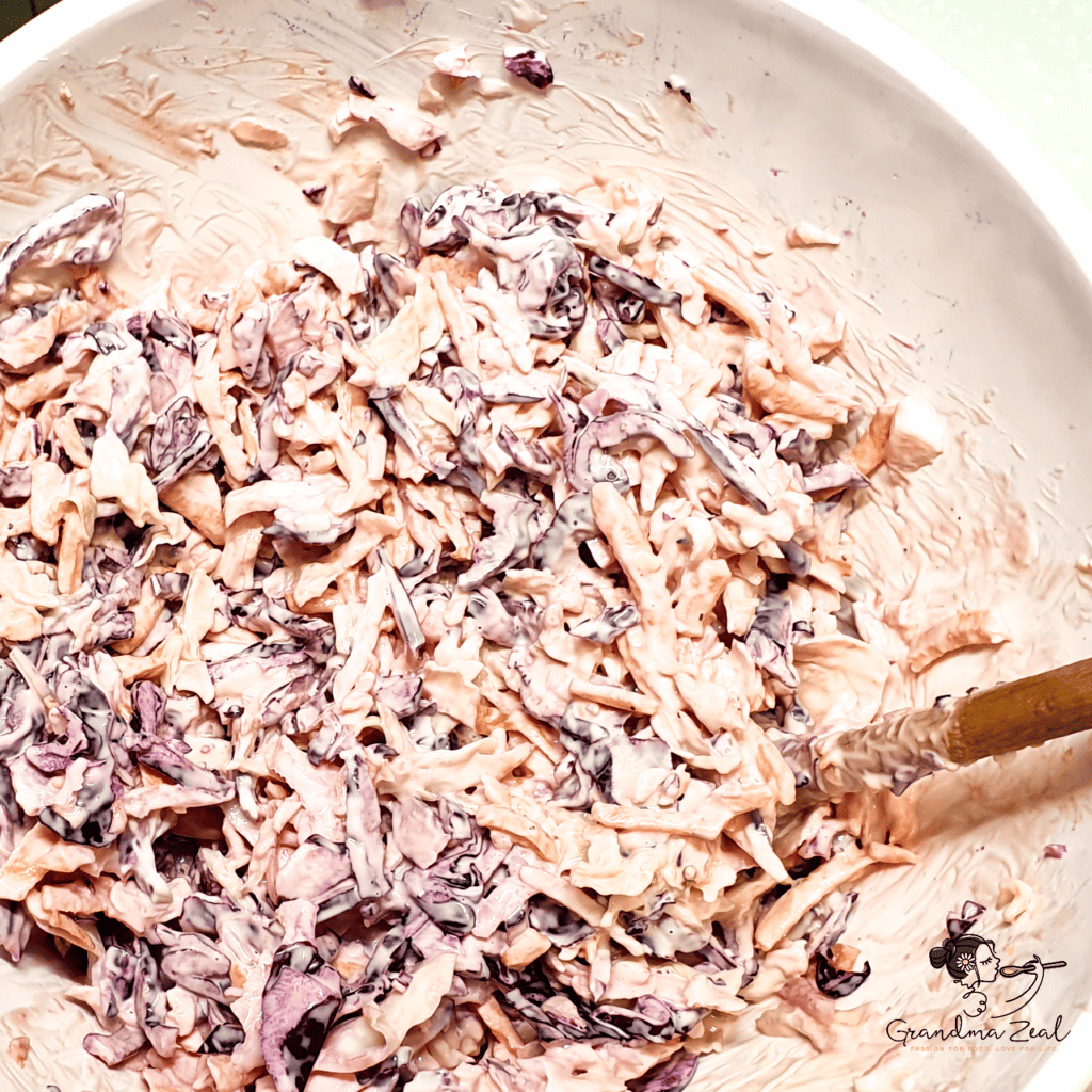 Easy creamy coleslaw with red and white cabbage, carrots, and dressing mixed in a bowl