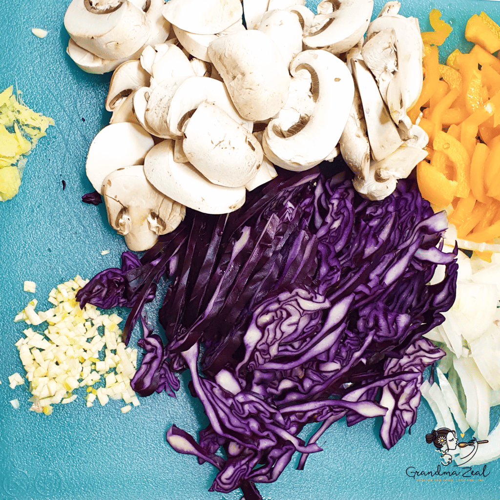 Sliced red cabbage, bell pepper, mushrooms and chopped garlic and ginger, ready for cooking