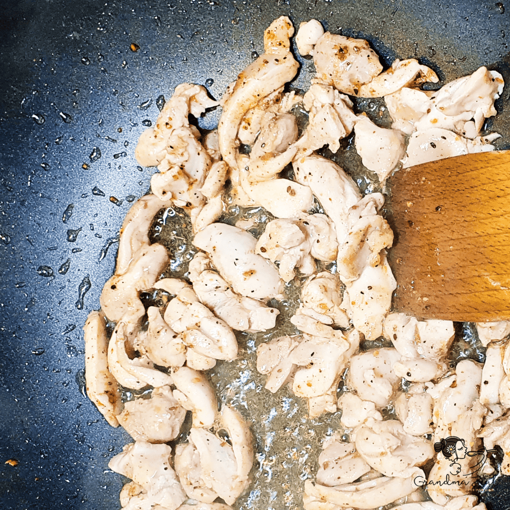 Stir-frying chicken strips in sesame oil with Chinese five-spice