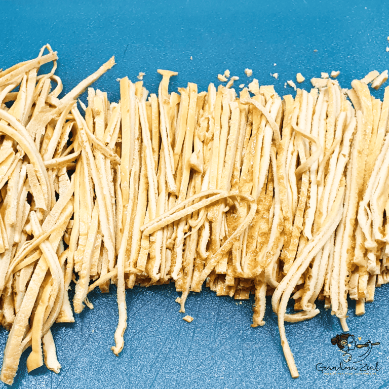 Thinly sliced homemade high-fibre pasta noodles on a wooden chopping board, ready to use in low-carb meals.
