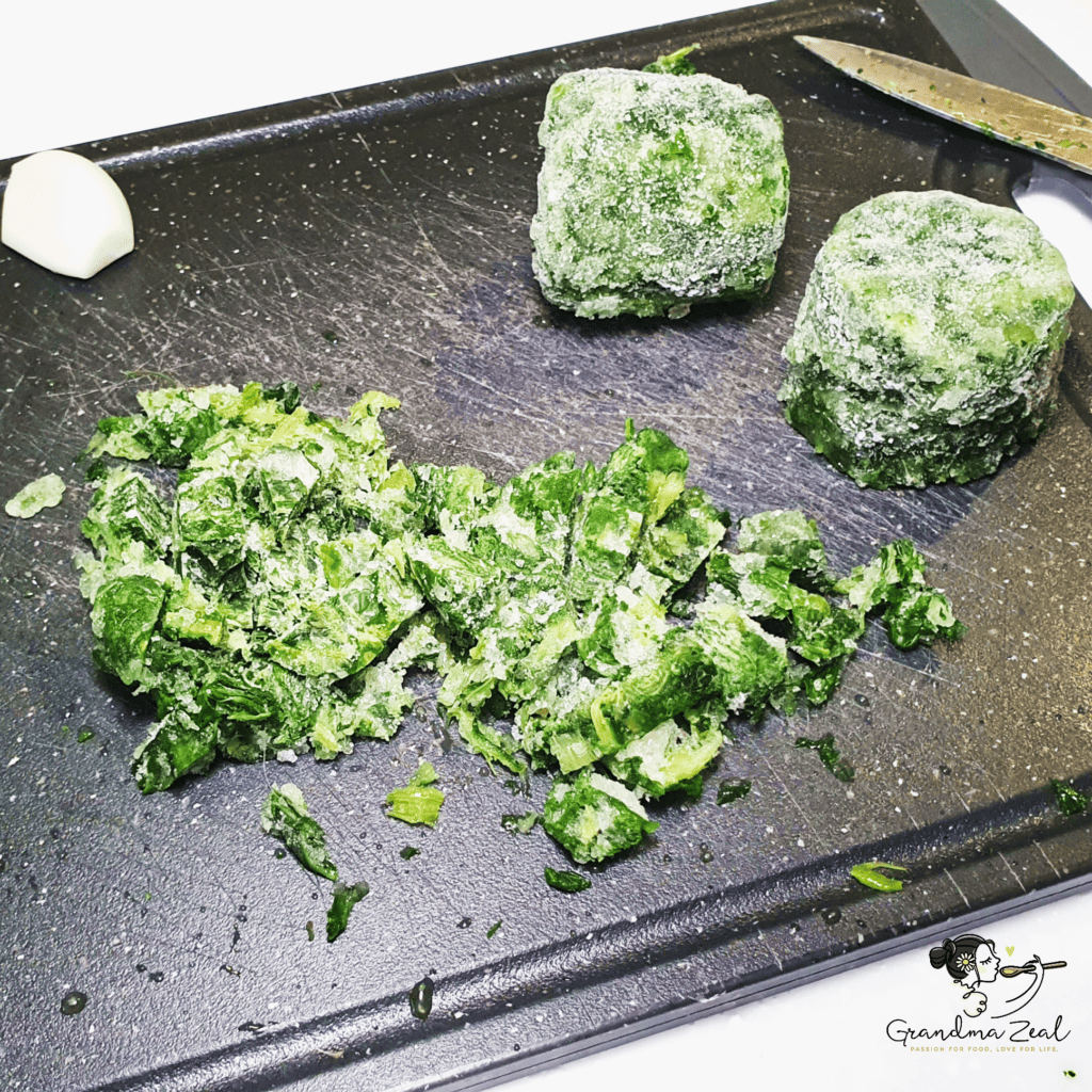 Chopping frozen whole-leaf spinach to break up tough strings before cooking.
