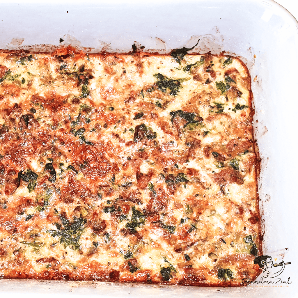 Freshly baked spinach and bacon crustless quiche in a baking pan, golden and set, ready to serve.