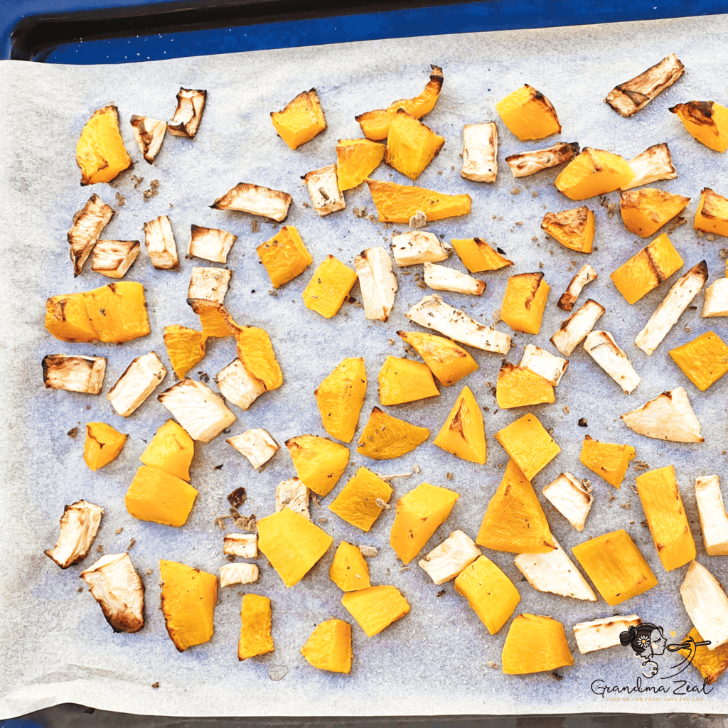 Freshly roasted squash and root vegetables on a baking tray, golden and caramelised.