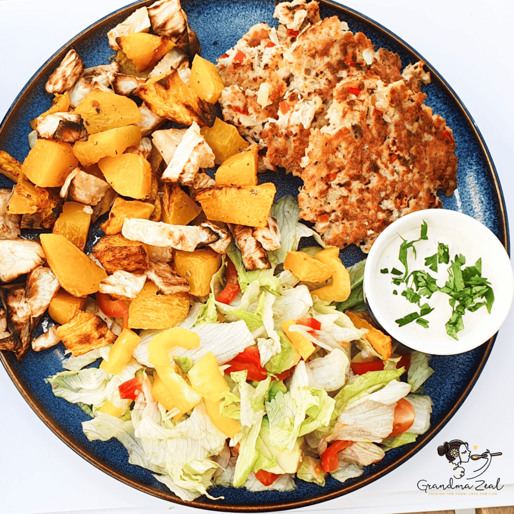 Healthy dinner plate with roasted root vegetables, salmon cakes, and a fresh side salad.