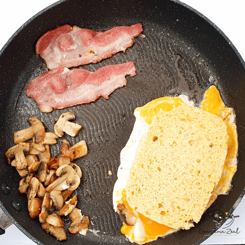 Bacon, mushrooms, and fried egg with 90-second microwave bread cooking together in a frying pan