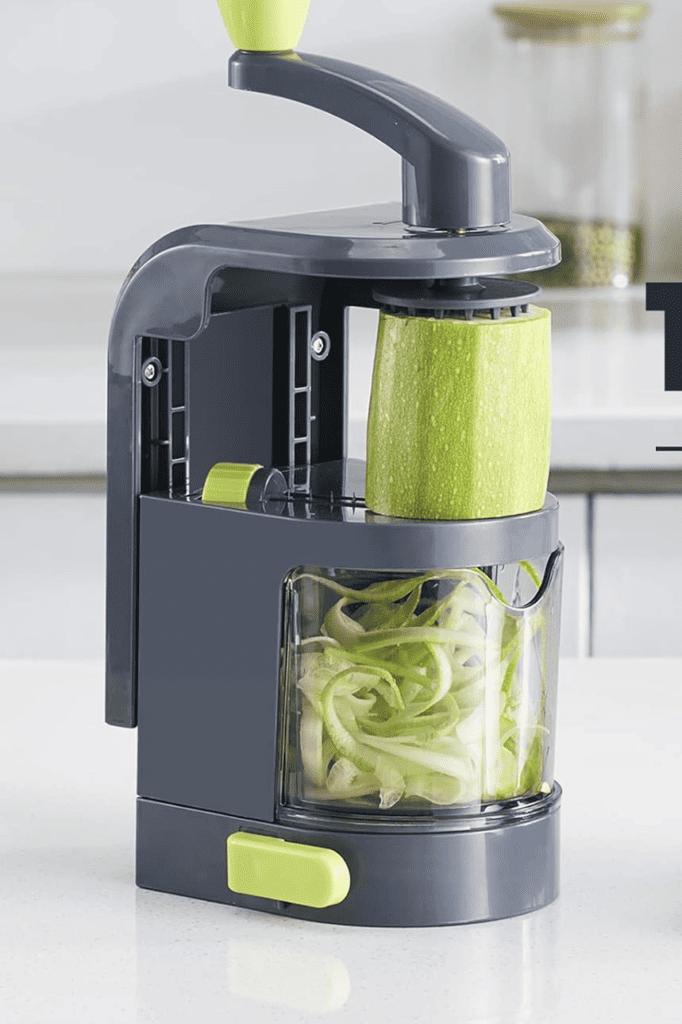 Making courgette zoodles using a hand spiraliser on a kitchen counter.