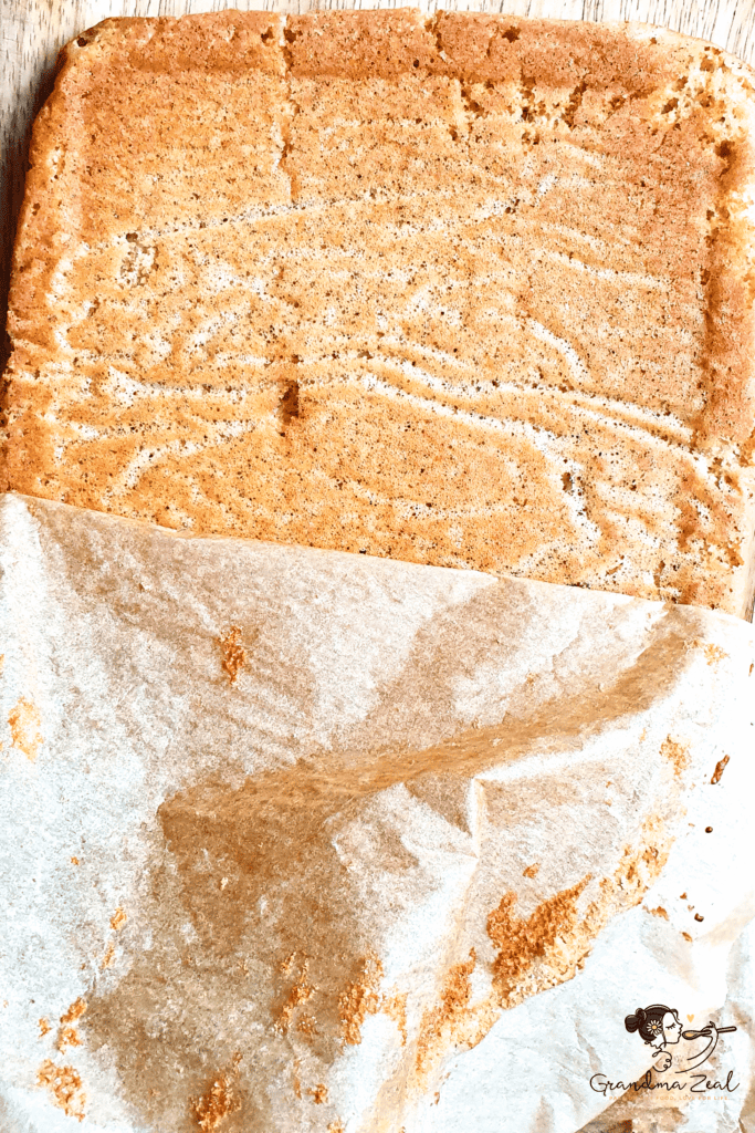 Peeling parchment paper off a rectangular low-carb coffee walnut cake