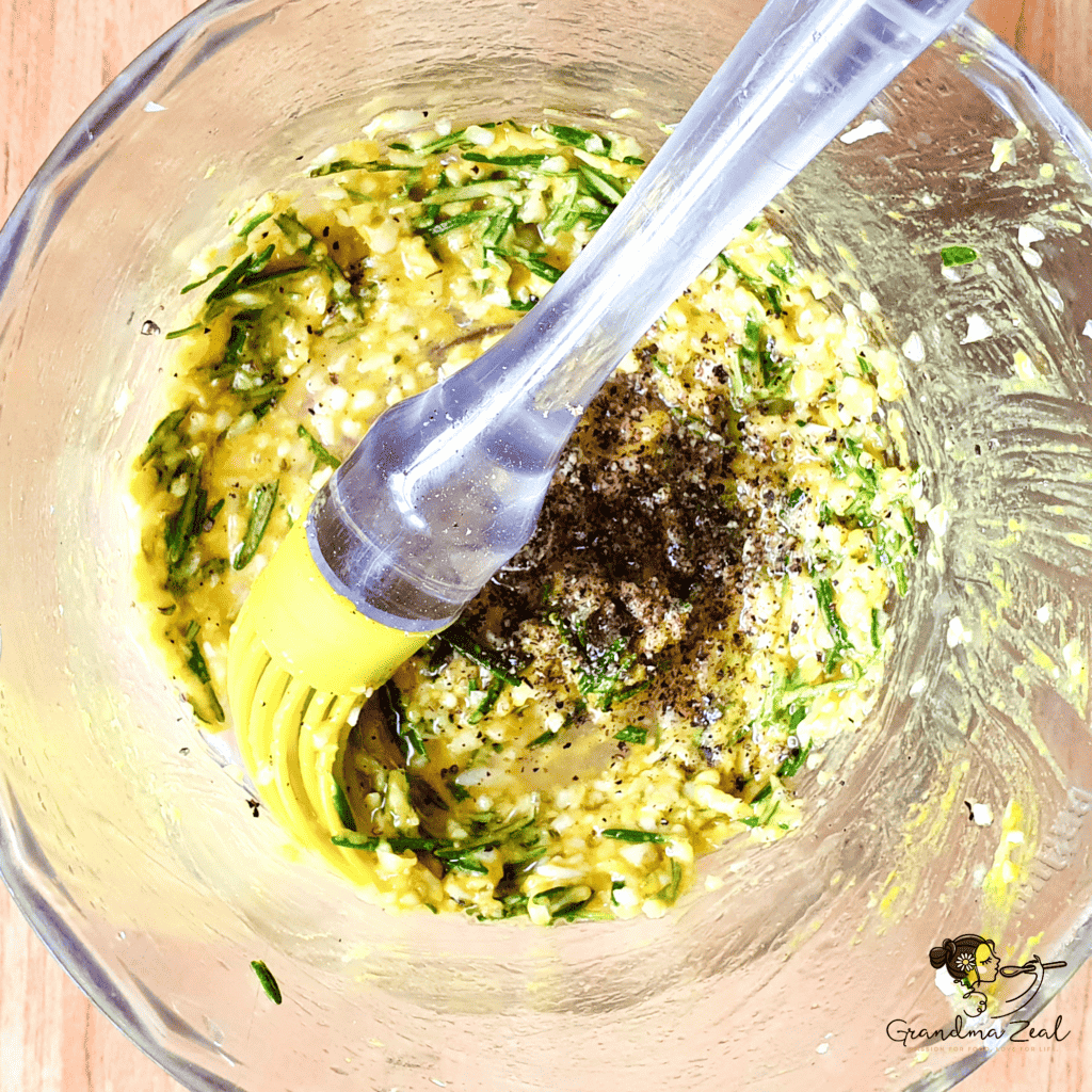 Close-up of rosemary and garlic marinade with mustard, olive oil, and black pepper in a bowl