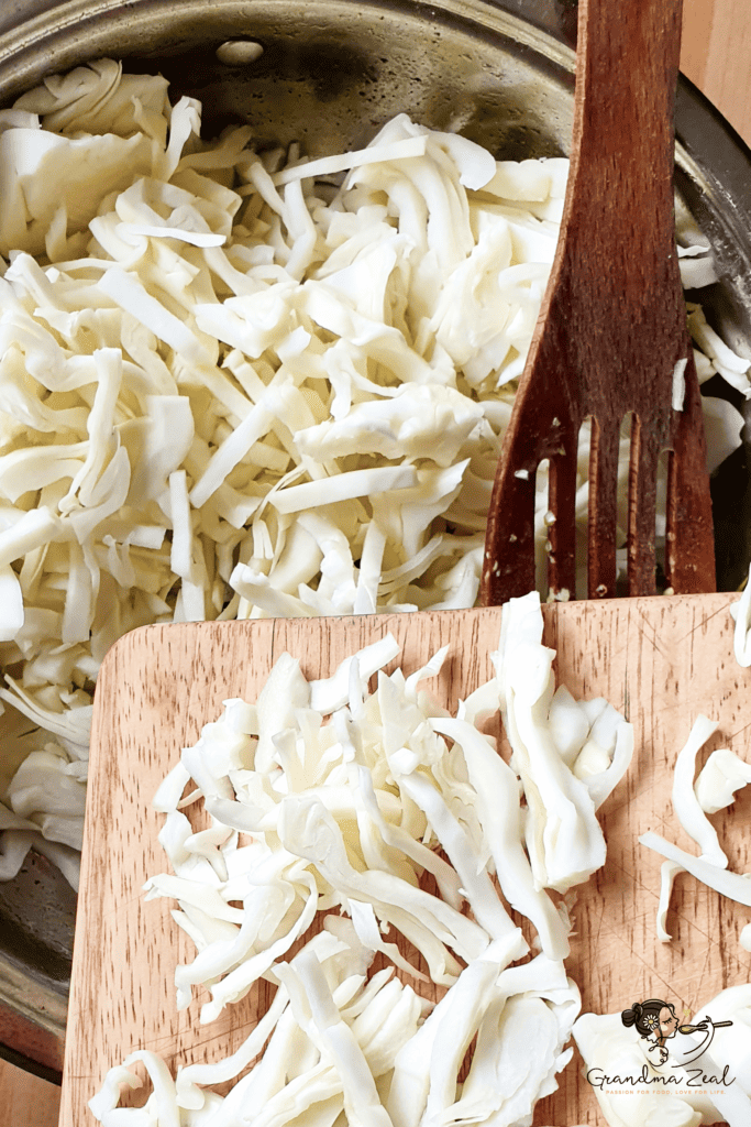 Adding shredded cabbage into a wide cooking pot.