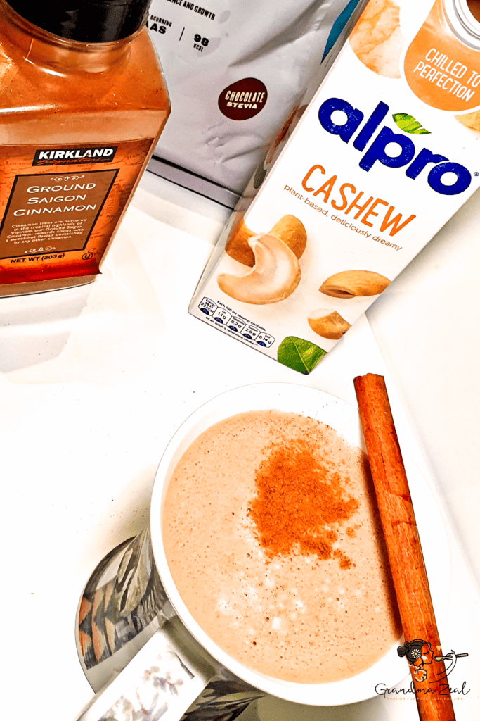 Ingredients for high-protein hot chocolate with cashew milk, protein powder, and a cinnamon-topped mug