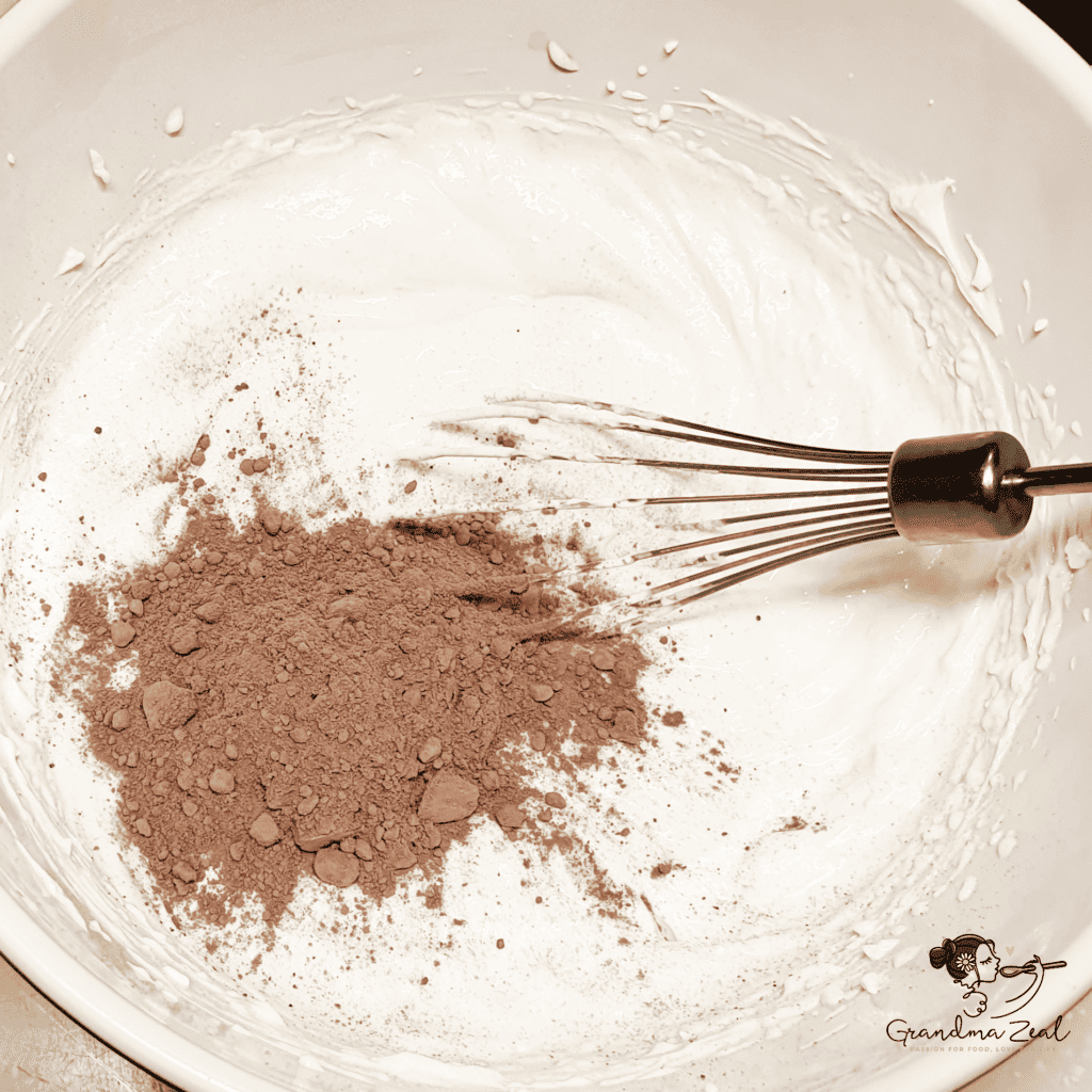 Creamy mascarpone frosting with cacao being whisked until smooth