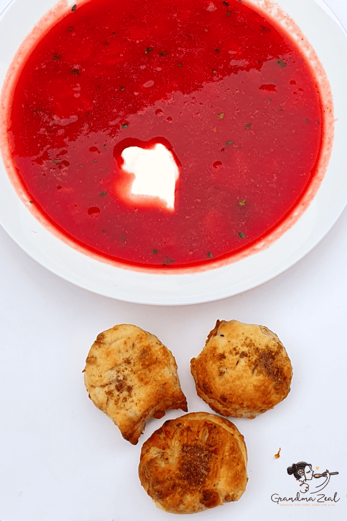 Deep plate of beetroot soup topped with sour cream and served with potato dumplings