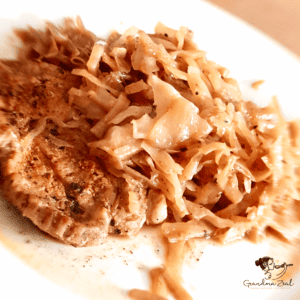 Close-up image of sautéed cabbage served with a slice of roast pork.