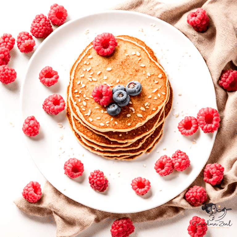 Stack of oat bran pancakes topped with raspberries and blueberries, viewed from above