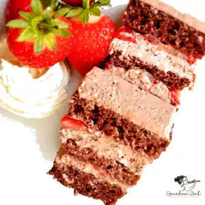 Slice of almond flour chocolate cake with strawberries and whipped cream on a white plate