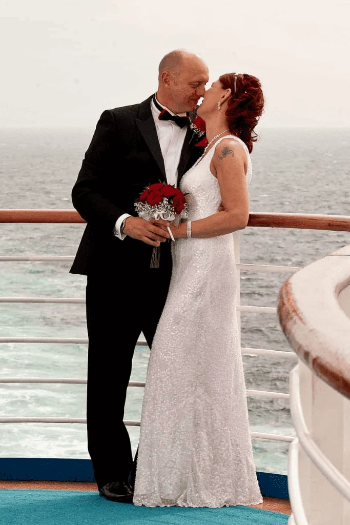 Helena with her husband on their wedding day at the back of a cruise ship, celebrating at sea