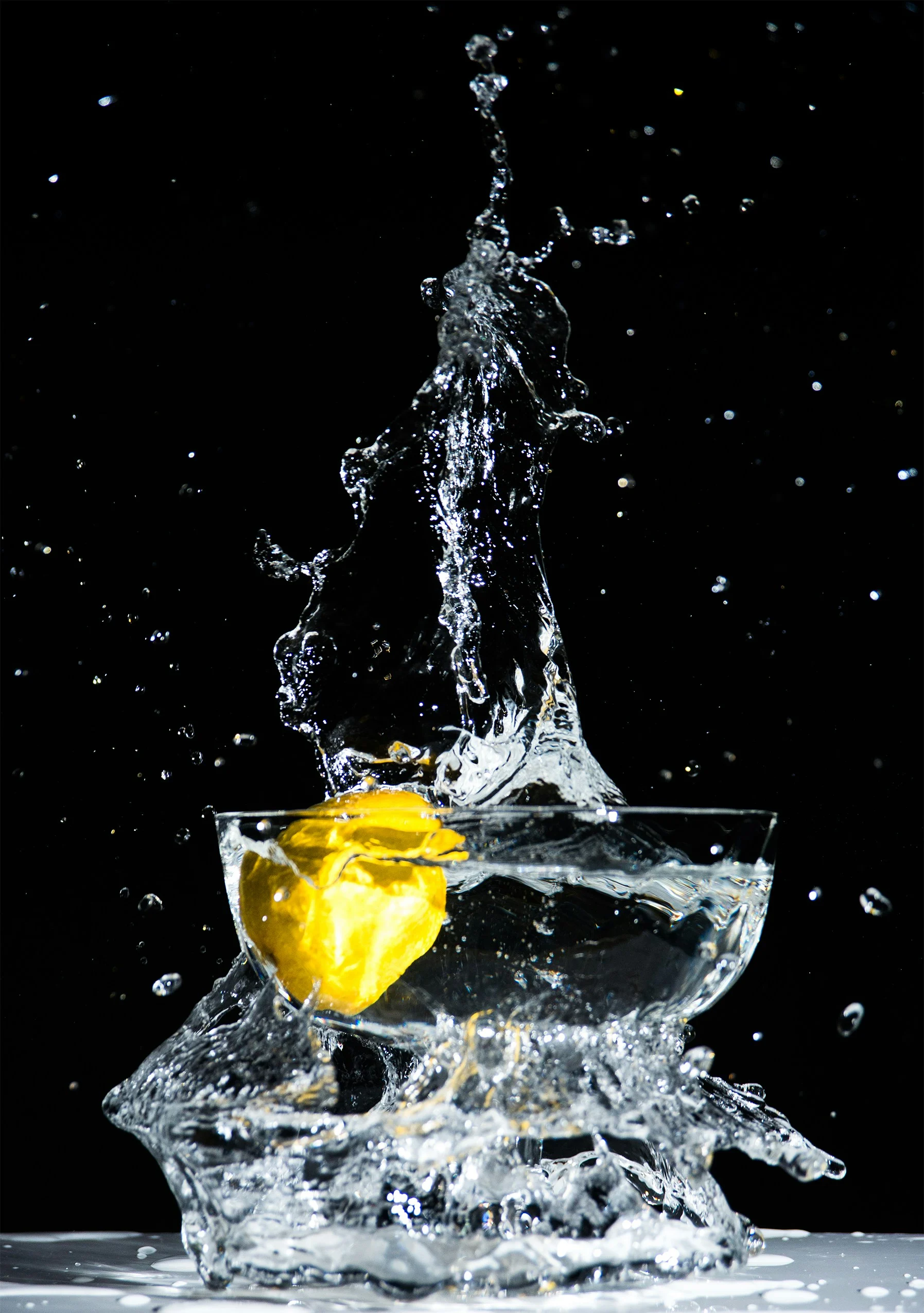 7 AMAZING HEALTH BENEFITS OF DRINKING WATER Lemon splashing into a glass of water on a black background, highlighting the refreshing impact of staying hydrated