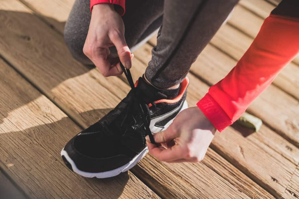 close up view of a person tying their shoelaces on wooden-floor
