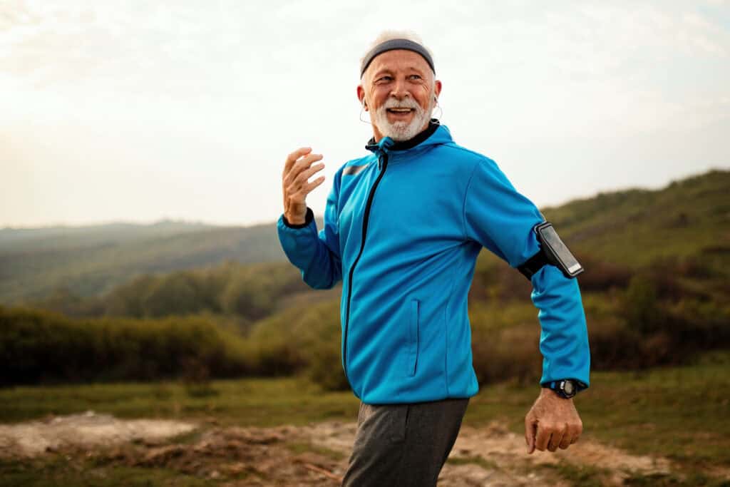Happy senior runner jogging in nature and enjoying in healthy lifestyle.