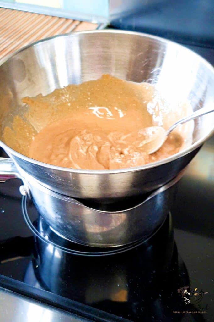 Nut butter warmed in a bowl over simmering water using the double boiler method to mix separated oil for low-carb protein bars recipe.